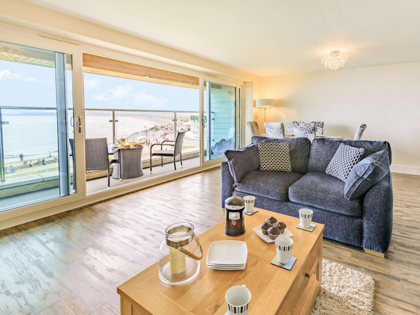 Un salon moderne doté d’une grande porte-fenêtre coulissante donnant sur un balcon avec vue sur la mer.