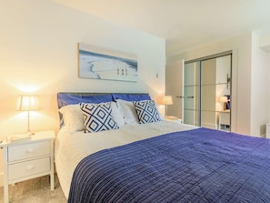 A bedroom with a bed, two bedside lamps, a nightstand, a large window, and a door. - 2 Bed in Bideford (oc-seasa) (Westward Ho!)