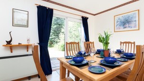 A dining room with a wooden table set for six, blue dinnerware, and a potted plant. - 3 Bed in Inverness (oc-in633) (Balnain)