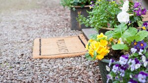 A gravel path leading to a door mat and two flower pots with various flowers. - 3 Bed in Inverness (oc-in633) (Balnain)