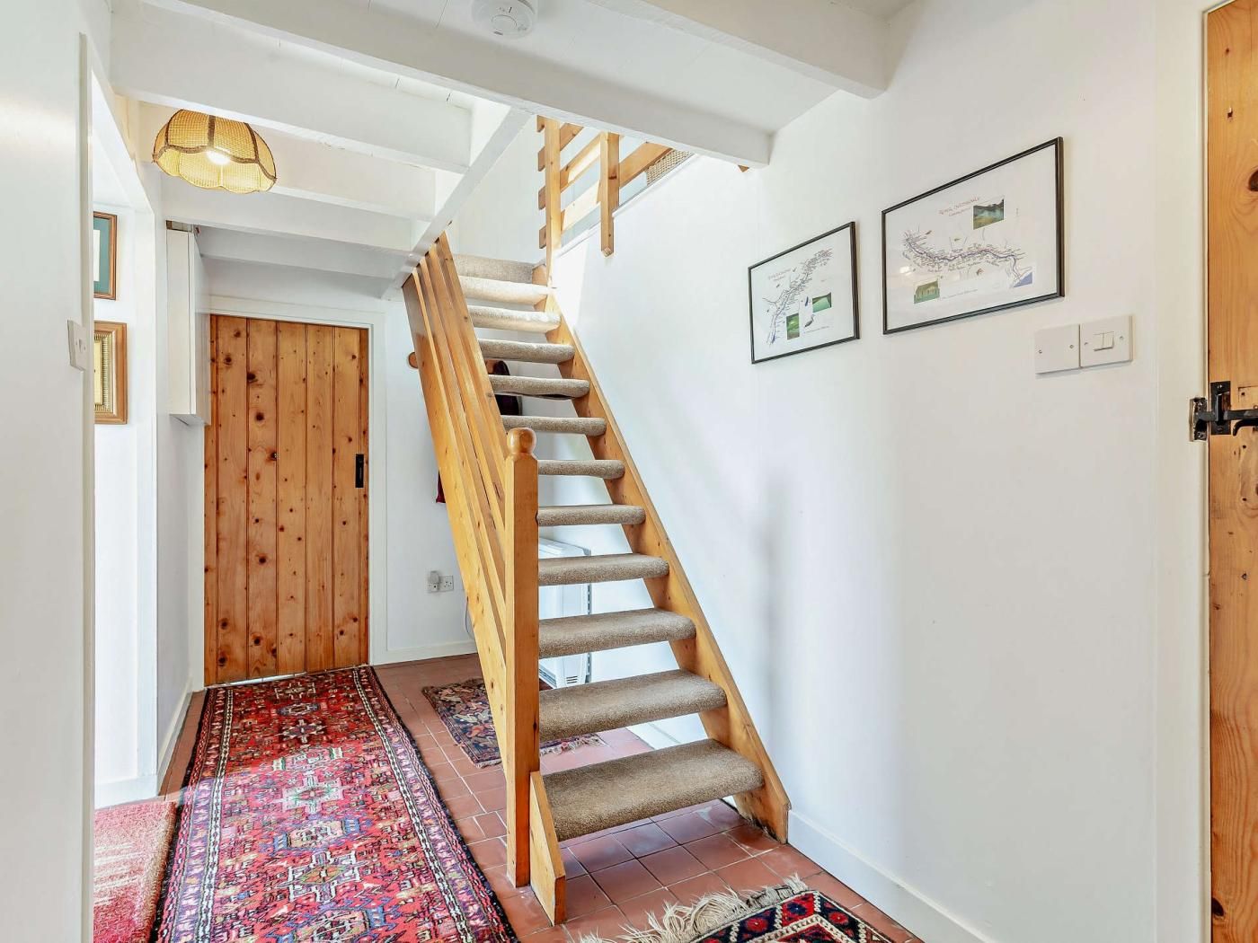 Una escalera con barandillas de madera y peldaños alfombrados que conduce a una habitación con una puerta.