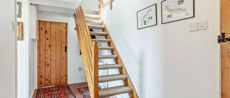 Una escalera con barandillas de madera y peldaños alfombrados que conduce a una habitación con una puerta.