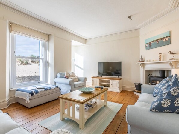 Ein Wohnzimmer mit großem Fenster, Fernseher, Kamin und einer Couch.