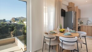 Een moderne keuken met een ingebouwde televisie, een eethoek met een tafel en stoelen, en een balkon met uitzicht op het landschap.