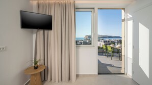 Een moderne kamer met een televisie, een raam, een plant en uitzicht op een stadsbeeld.