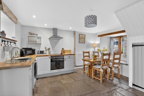 A compact kitchen with a central island, a dining area with wooden chairs, and a view through a window. - 2 Bed in Taunton (oc-conco) (Monkton Heathfield)