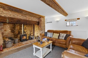A cozy living room with a stone fireplace, leather sofa, and a coffee table. - 2 Bed in Taunton (oc-conco) (Monkton Heathfield)