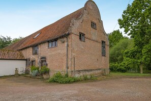 A brick building with a sloped roof, a small attached structure, and a gravel driveway. - 1 Bed in Norwich (oc-stbn8) (Mulbarton)