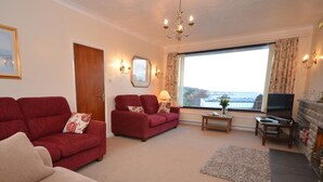 A living room with two red sofas, a beige sofa, a television, and a fireplace. - 2 Bed in Bideford (oc-sandb) (Instow)