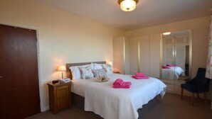A hotel room with a bed, bedside table, lamp, and a large mirror. - 2 Bed in Bideford (oc-sandb) (Instow)