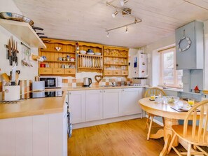 Eine Küche mit Holzausstattung, einer zentralen Kochinsel und einem Essbereich mit Tisch und Stühlen.