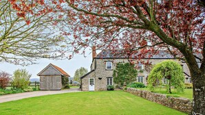 A stone building with a grassy lawn, a wooden barn, and a tree with red leaves. - 3 Bed in Axminster (oc-wonov) (Musbury)