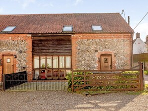 Ein Backsteinhaus mit einem Ziegeldach, einer Holztür und einem Metallgitter.
