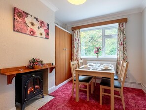 A cozy room with a fireplace, a dining table set for four, and a window with curtains. - 2 Bed in Dereham (oc-shrn8) (Scarning)