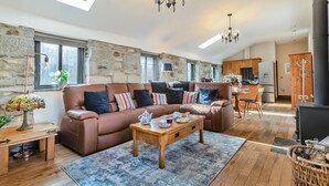Un salon chaleureux avec un canapé, une table basse et un coin repas comprenant une table et des chaises.
