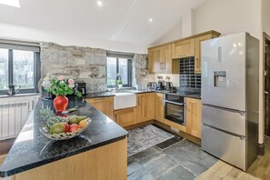 Eine moderne Küche mit Granitarbeitsplatten, Holzschränken, einem eingebauten Backofen und einem Edelstahlkühlschrank.
