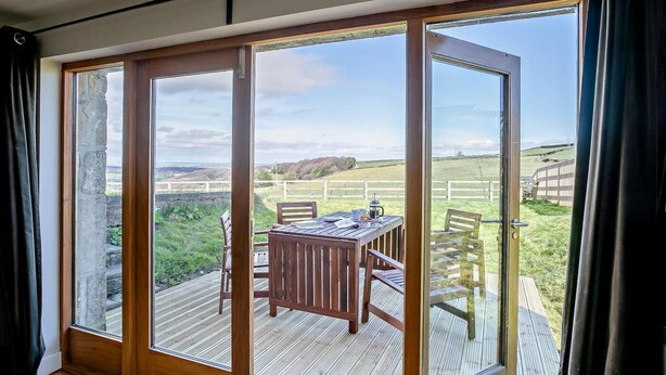 A room with a sliding glass door leading to an outdoor deck with a table and chairs. - 2 Bed in Holmfirth (oc-emley) (New Mill)