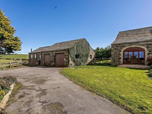 A stone building with a paved driveway and a grassy area. - 2 Bed in Holmfirth (oc-emley) (New Mill)