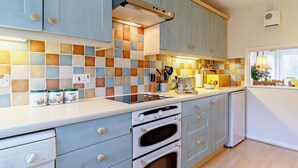 Una cocina con armarios azul claro, salpicadero de azulejos y una ventana con vistas.