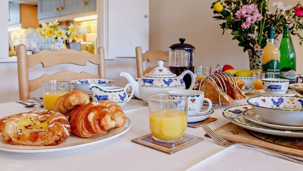 Desayuno con cruasanes, café, jugo y un florero.