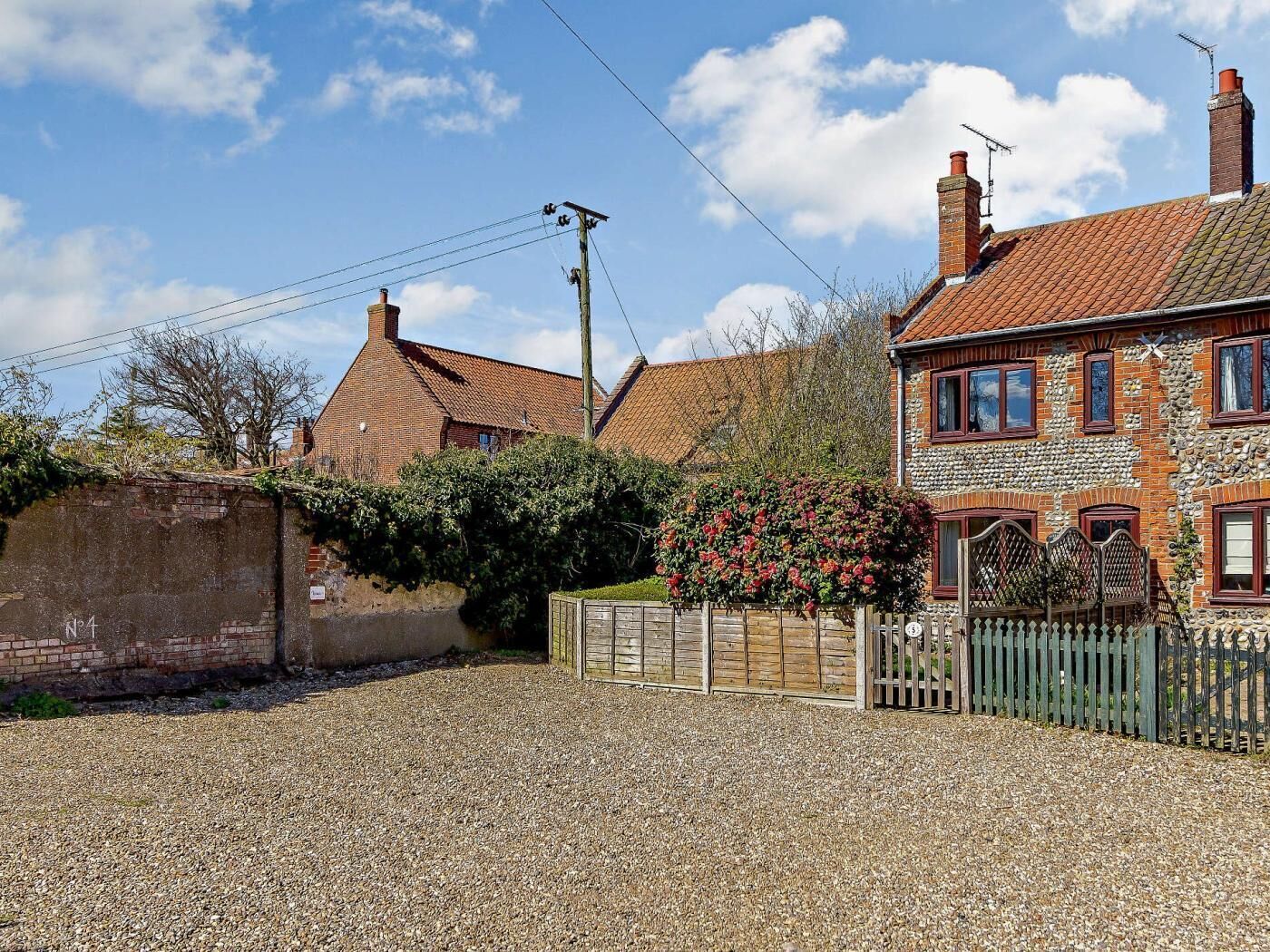 A residential area with houses, a gravel driveway, and a wooden fence.