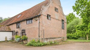 Un bâtiment en briques avec un toit en pente, un petit porche et une allée gravillonnée.