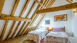 Une chambre avec deux lits, un plafond en bois et une fenêtre.