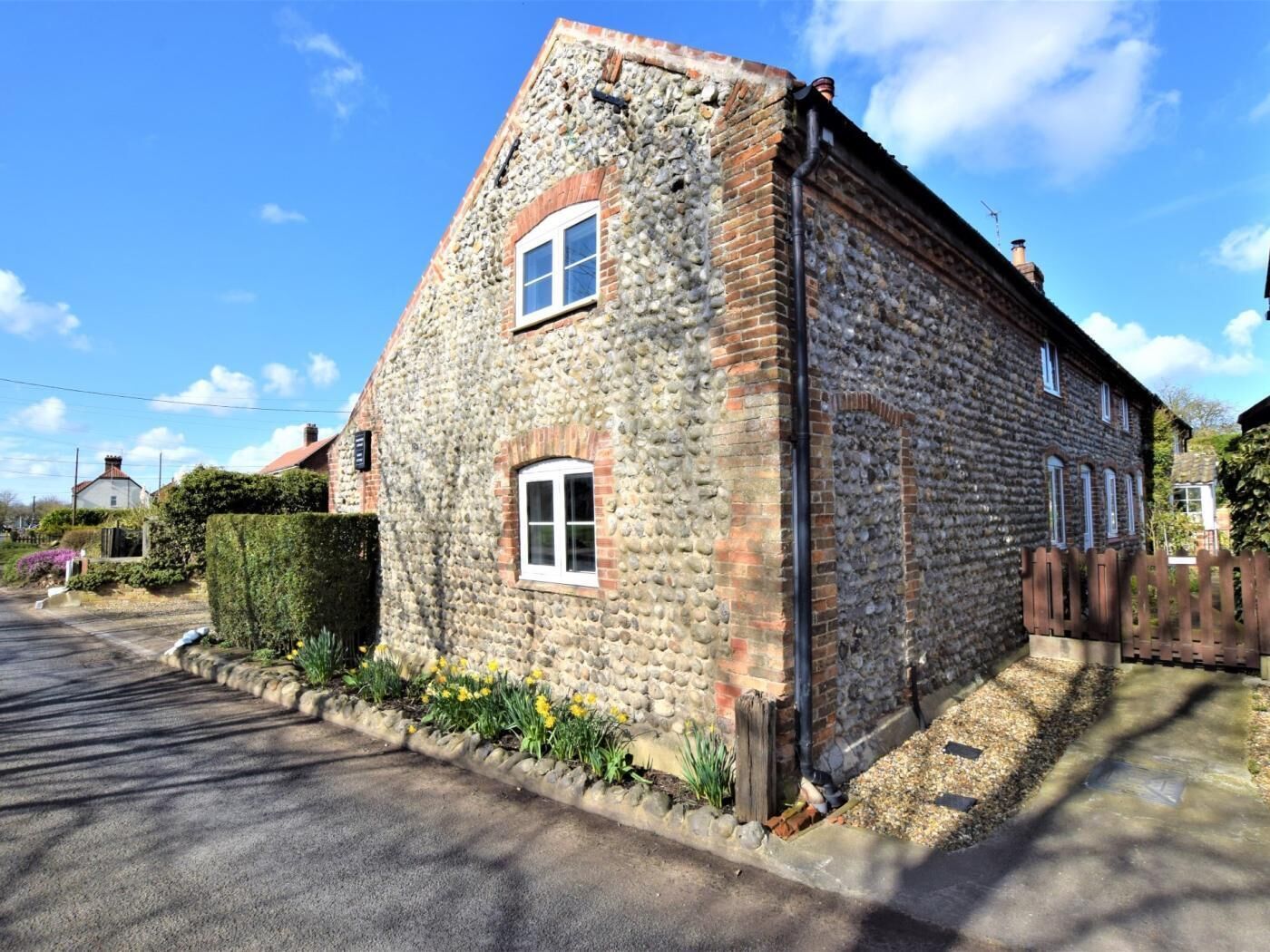 A stone building with a pitched roof, a small window, and a wooden fence.