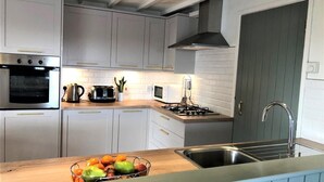 Eine moderne Küche mit weißen Schränken, einem eingebauten Backofen, einer Mikrowelle, einem Gasherd und einem Spülbecken.