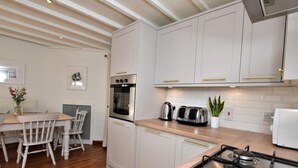 Eine moderne Küche mit weißen Schränken, einem Holztisch und einem Gasherd.