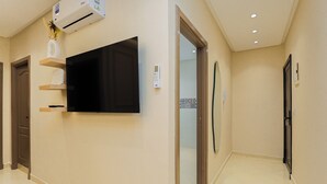 A hallway with a mounted TV, an air conditioning unit, and a door leading to another room. - TGV 7 min Corniche Plage WiFi fibre (Tanger)