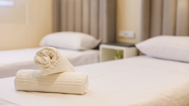 A hotel room with two beds, each with a headboard, a folded towel on the bed, and a nightstand with a lamp. - TGV 7 min Corniche Plage WiFi fibre (Tanger)