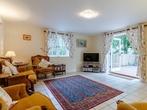 A living room with a sofa set, a television, a rug, and a window with curtains. - 2 Bed in Truro (oc-lrose) (Tregavethan)