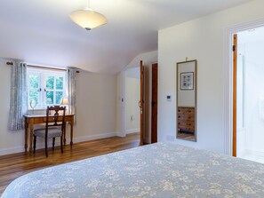 A bedroom with a bed, a desk with a chair, a window with curtains, and a door. - 2 Bed in Truro (oc-lrose) (Tregavethan)