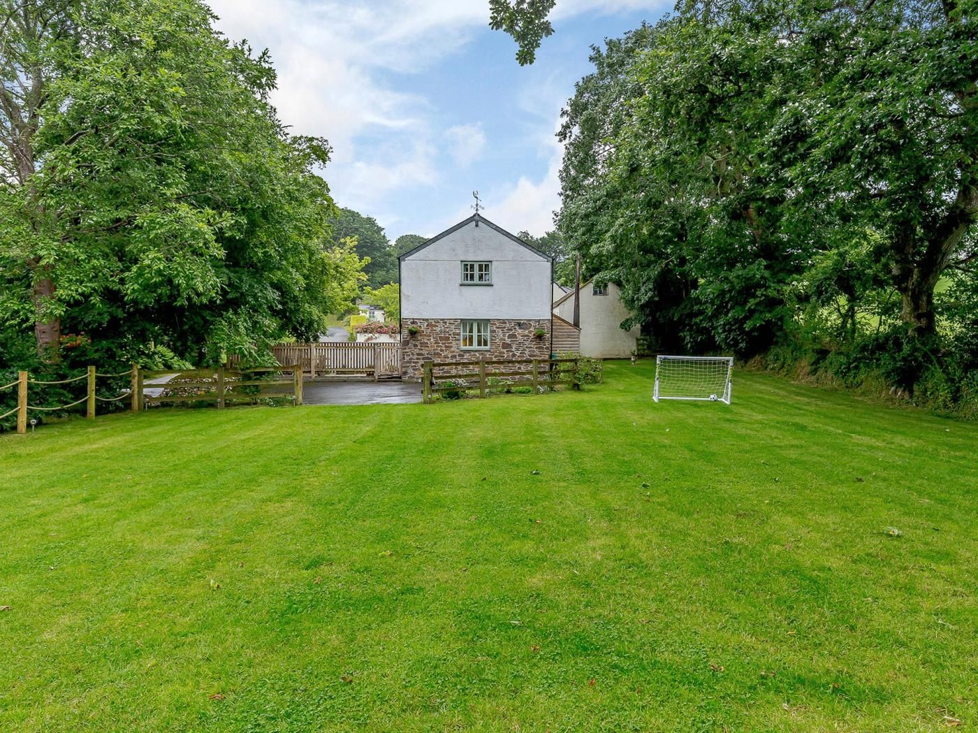 Ein Haus mit einer Stein-Fassade, einem Rasen und einem Fußballtor.