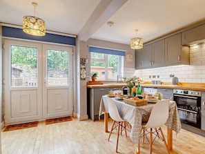 A modern kitchen with a dining area, wooden flooring, and a view of the outdoors. - 2 Bed in Northrepps (oc-dain8) (Northrepps)