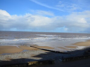 A beach with a pebbly shore, a wooden jetty, and the ocean under a partly cloudy sky. - 2 Bed in Northrepps (oc-dain8) (Northrepps)