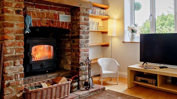 Ein gemütliches Zimmer mit Kamin aus Backsteinen, einem Fernseher und einem Bücherregal.