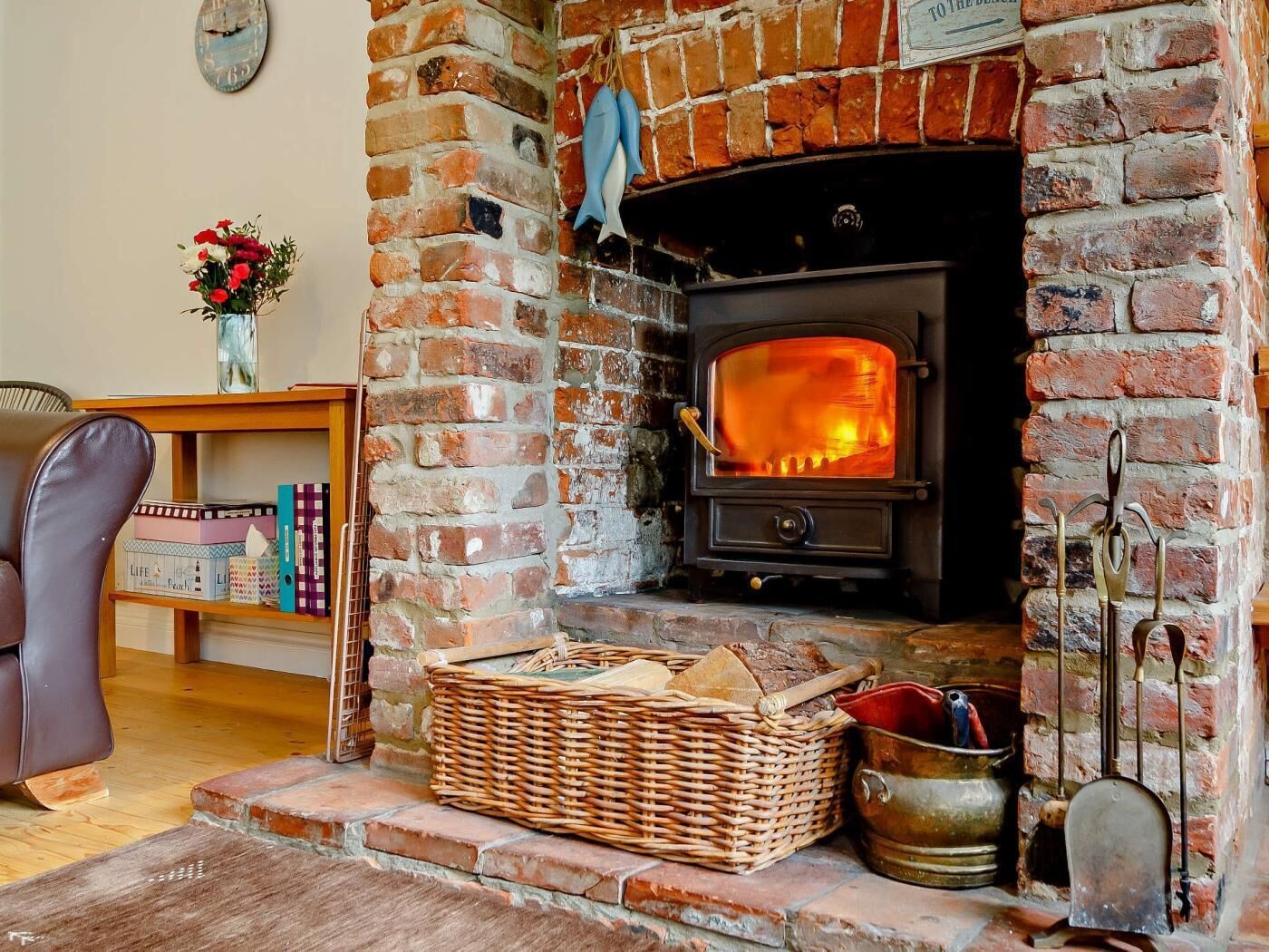 A brick fireplace with a wood-burning stove, a wicker basket, and a metal bucket.