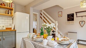 Eine Küche mit Esstisch, gedeckt für das Frühstück, einem Kühlschrank und einer Treppe, die nach oben führt.