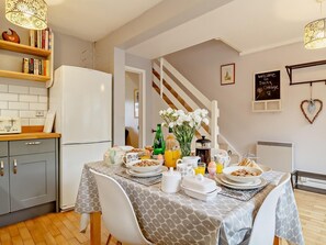 A kitchen with a dining table set for breakfast, a refrigerator, and a staircase leading upstairs. - 2 Bed in Northrepps (oc-dain8) (Northrepps)