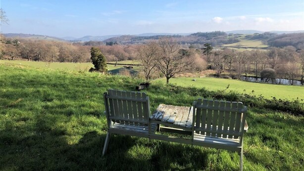 Un banc placé face à un paysage pittoresque, avec des collines et des arbres.