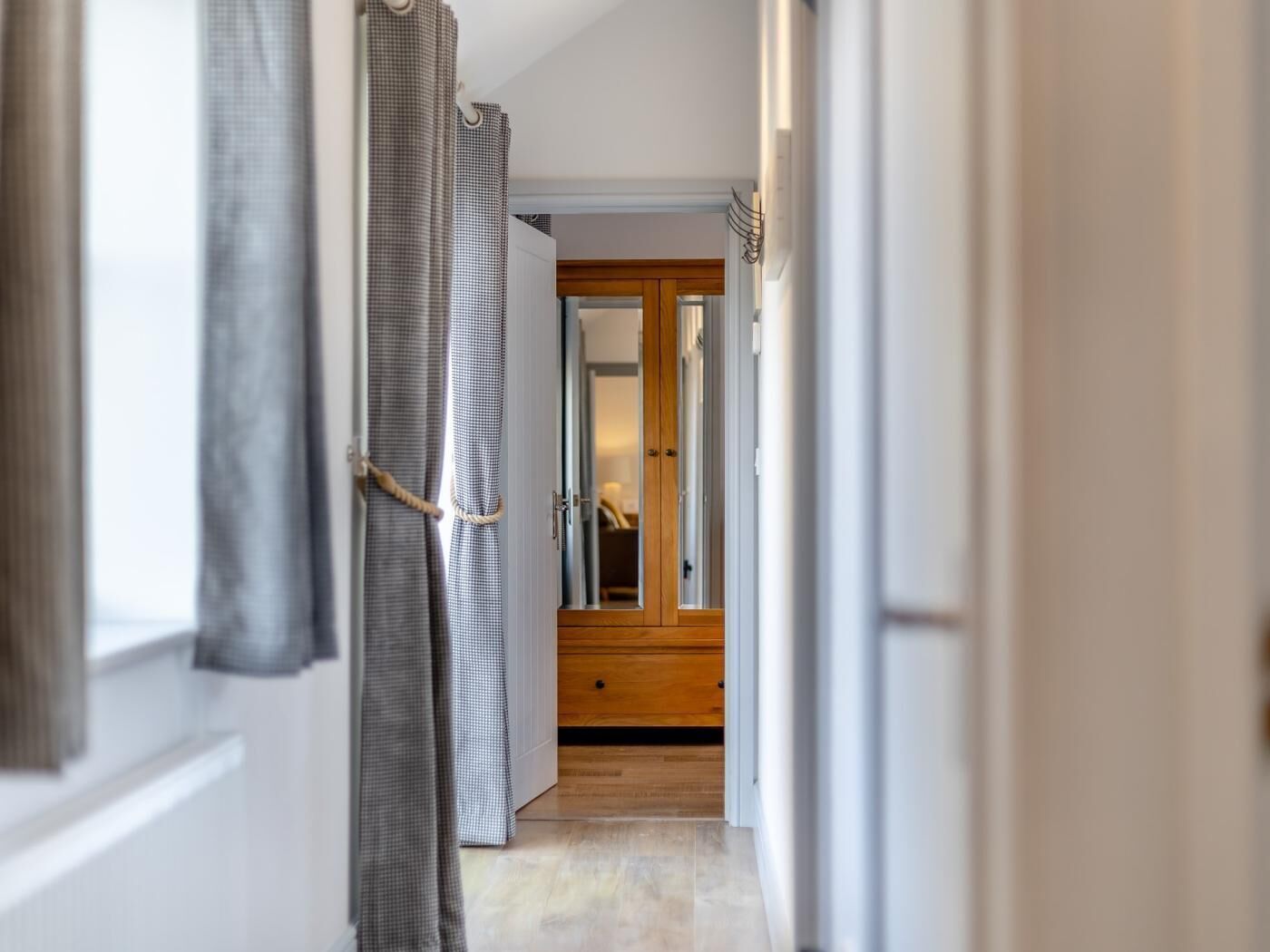 Un pasillo con una puerta de madera, una cortina a cuadros y un piso de baldosas.
