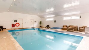 An indoor swimming pool with a clear ceiling, a lifebuoy, a hot tub, and seating areas. - 1 Bed in Ilfracombe (oc-fiddl) (Berrynarbor)