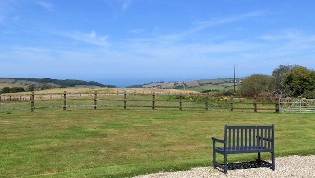 A bench in a grassy field with a view of rolling hills and a distant coastline. - 1 Bed in Ilfracombe (oc-fiddl) (Berrynarbor)