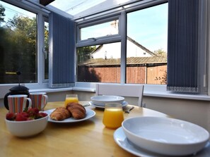 A breakfast table with croissants, fruit, and orange juice, set near a window with a view of a house and trees. - 1 Bed in Holsworthy (oc-wscot) (Pancrasweek)