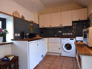 A compact kitchen with white cabinets, a washing machine, a dishwasher, and a coffee maker. - 1 Bed in Holsworthy (oc-wscot) (Pancrasweek)