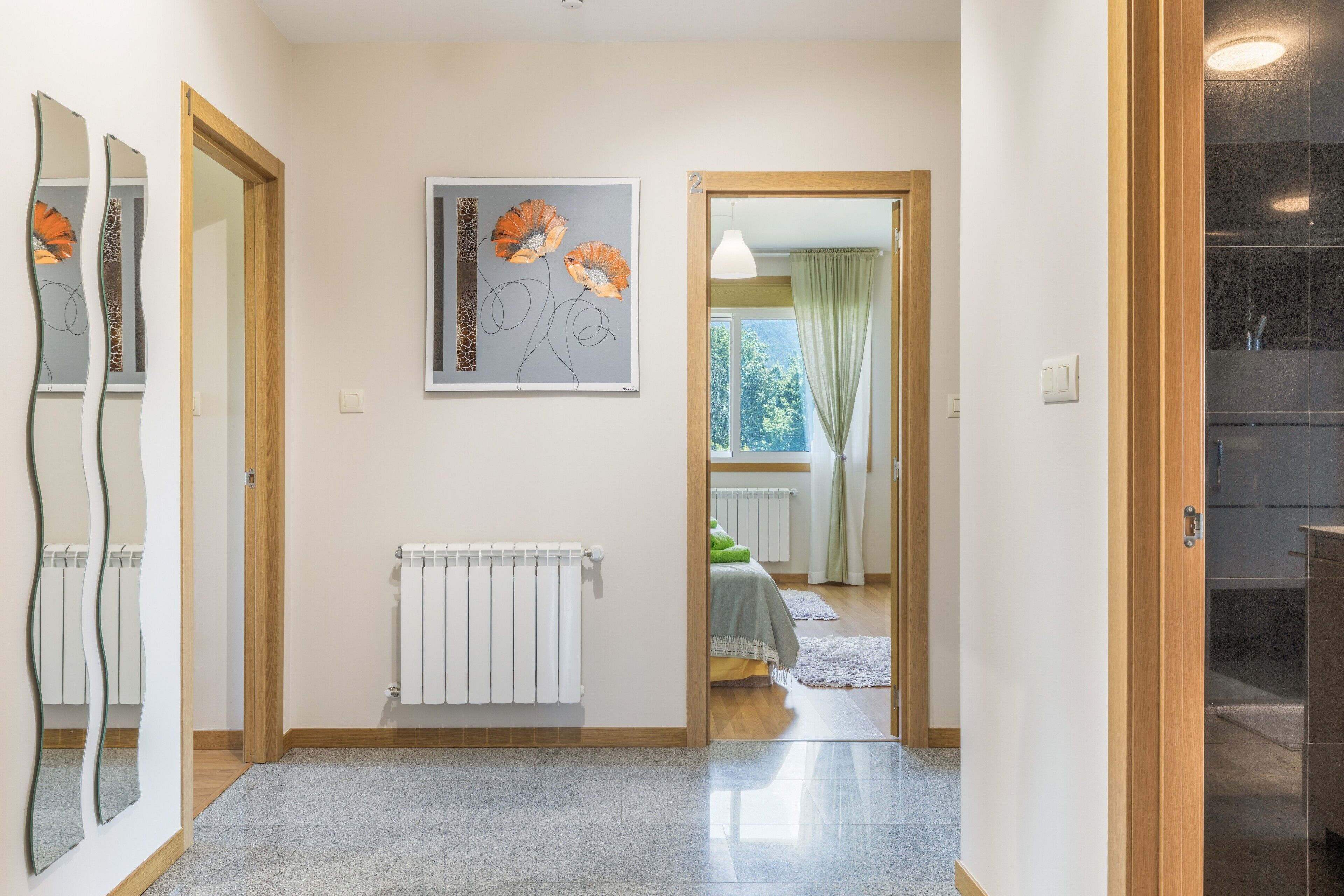 A hallway with a radiator, a framed artwork, and a door leading to a bedroom.