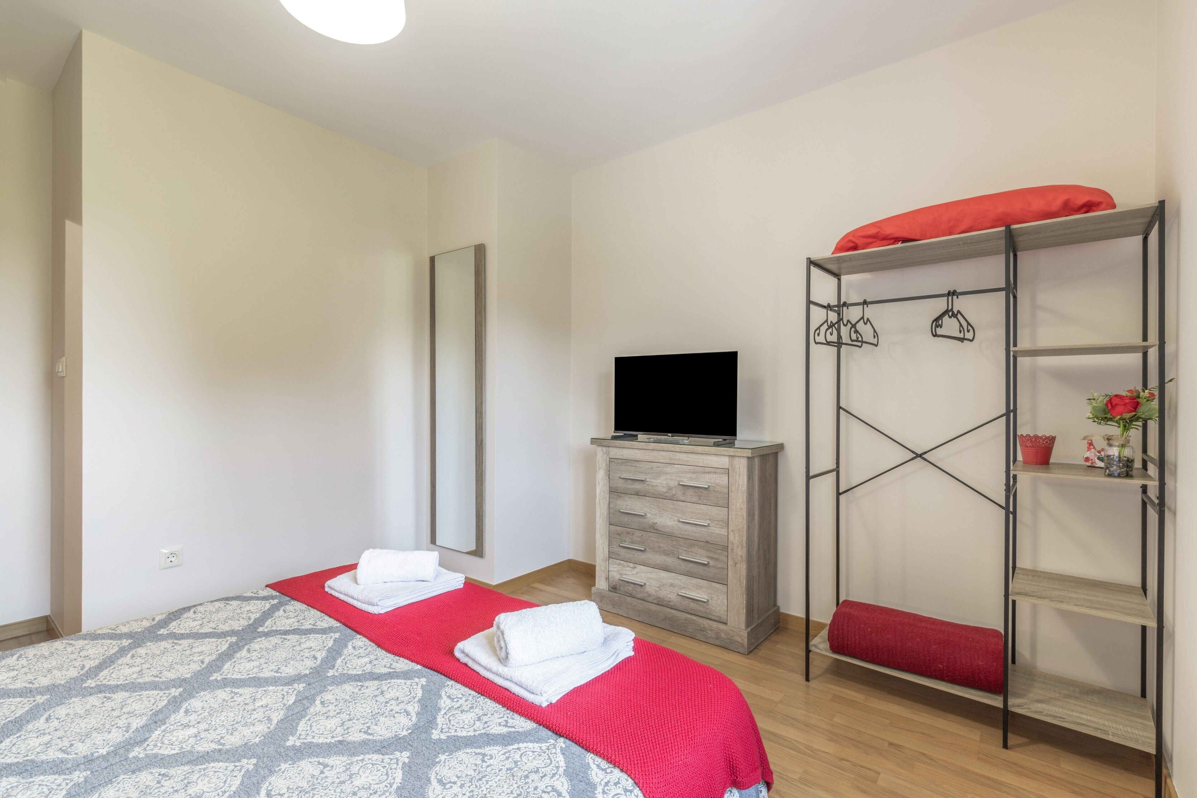 Ein Schlafzimmer mit einem Bett, einem Fernseher, einem Kleiderschrank und einer roten Regalwand.