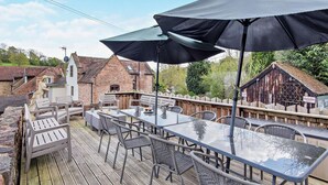 Une terrasse extérieure avec des tables et des chaises, une statue et une plateforme en bois.
